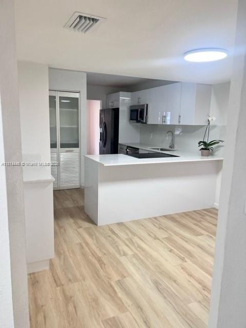 958 Mockingbird Ln Unit 511, Plantation, FL 33324 - kitchen with stainless steel microwave, black refrigerator with ice dispenser, a sink, light wood-type flooring, and a peninsula