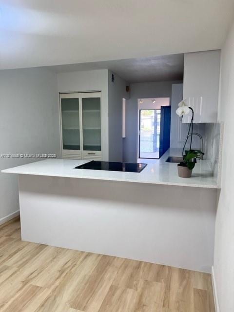 958 Mockingbird Ln Unit 511, Plantation, FL 33324 - kitchen with light wood-type flooring, black electric cooktop, baseboards, a peninsula, and light countertops