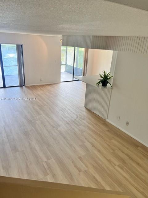 958 Mockingbird Ln Unit 511, Plantation, FL 33324 - spare room with baseboards, light wood-style floors, and a textured ceiling
