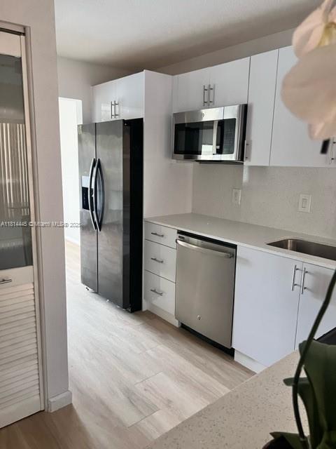 958 Mockingbird Ln Unit 511, Plantation, FL 33324 - kitchen with stainless steel appliances, light wood finished floors, light countertops, and white cabinetry