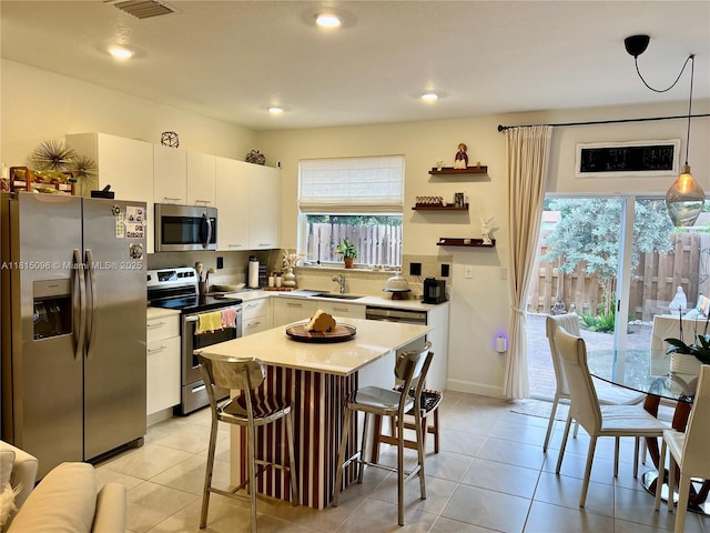 12254 NW 24th Pl, Miami, FL 33167 - kitchen featuring stainless steel appliances, plenty of natural light, a breakfast bar area, light countertops, and recessed lighting