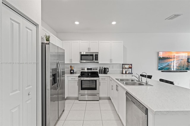 12945 SW 234th St, Homestead, FL 33032 - kitchen with stainless steel appliances, a sink, a peninsula, light tile patterned flooring, and white cabinets