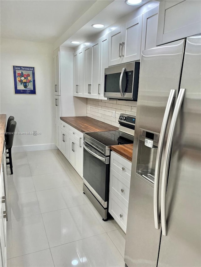 4001 Hillcrest Dr Unit 1014, Hollywood, FL 33021 - kitchen featuring appliances with stainless steel finishes, wooden counters, backsplash, light tile patterned floors, and white cabinetry