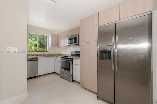 811 NW 3rd Ave, Fort Lauderdale, FL 33311 - kitchen with appliances with stainless steel finishes, light tile patterned floors, tasteful backsplash, light brown cabinetry, and light stone countertops
