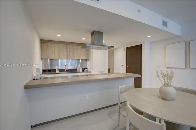 1000 Brickell Plz Unit 2705, Miami, FL 33131 - kitchen featuring island range hood, a peninsula, recessed lighting, modern cabinets, and a breakfast bar area