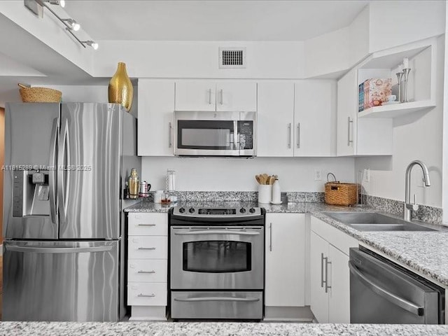 1532 Drexel Ave Unit 204, Miami Beach, FL 33139 - kitchen with appliances with stainless steel finishes, a sink, white cabinets, open shelves, and light stone countertops