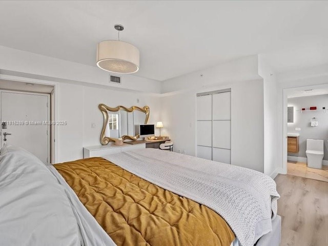 1532 Drexel Ave Unit 204, Miami Beach, FL 33139 - bedroom with wood finished floors, ensuite bathroom, baseboards, and a closet