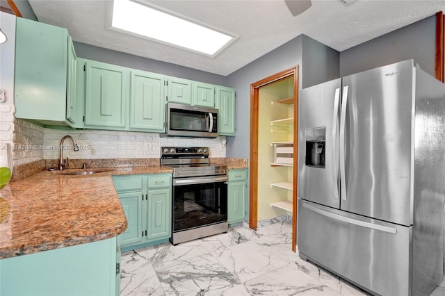 2398 SE Bordeaux Ct, Port St Lucie, FL 34952 - kitchen featuring stainless steel appliances, a sink, light marble finish flooring, backsplash, and green cabinets