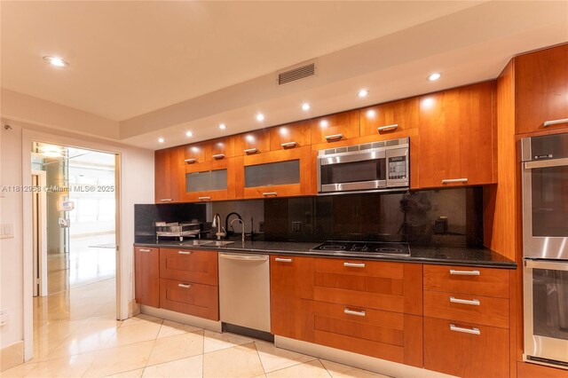 10205 Collins Ave Unit 401, Bal Harbour, FL 33154 - kitchen with stainless steel appliances, modern cabinets, brown cabinetry, backsplash, and glass insert cabinets