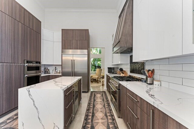 127 Swan Ave, Plantation, FL 33324 - kitchen with high quality appliances, modern cabinets, ornamental molding, a kitchen island, and backsplash