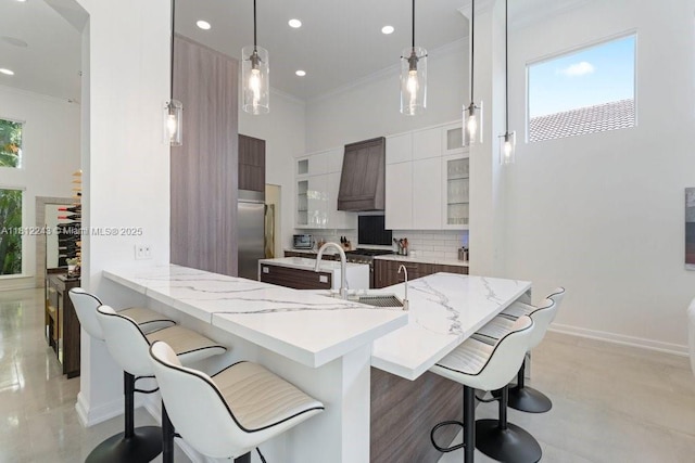 127 Swan Ave, Plantation, FL 33324 - kitchen featuring modern cabinets, a kitchen bar, crown molding, backsplash, and stainless steel built in refrigerator
