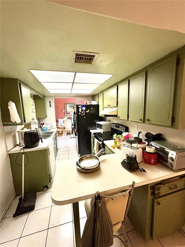 4781 NW 19th Ct, Lauderhill, FL 33313 - kitchen with stainless steel electric range, green cabinetry, under cabinet range hood, freestanding refrigerator, and light countertops