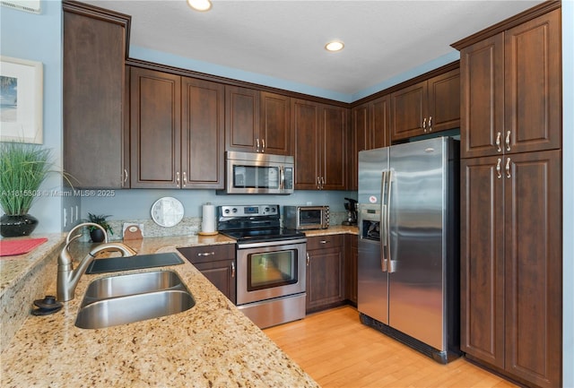 7702 Paddock Pl, Davie, FL 33328 - kitchen featuring appliances with stainless steel finishes, light wood finished floors, dark brown cabinetry, light stone counters, and recessed lighting