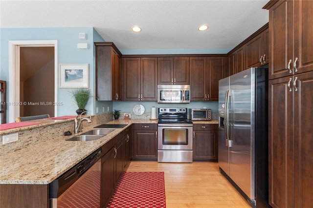 7702 Paddock Pl, Davie, FL 33328 - kitchen with appliances with stainless steel finishes, light wood-type flooring, a peninsula, light stone counters, and recessed lighting