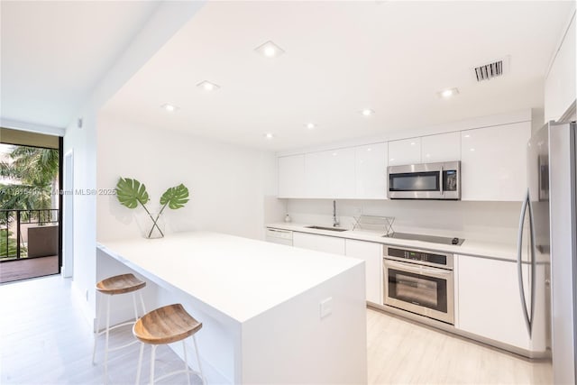 181 Crandon Blvd Unit 306, Key Biscayne, FL 33149 - kitchen featuring stainless steel appliances, modern cabinets, a sink, white cabinetry, and a breakfast bar