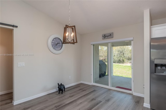 16365 SW 47th Ter, Ocala, FL 34473 - unfurnished dining area with a chandelier, wood finished floors, baseboards, and a barn door