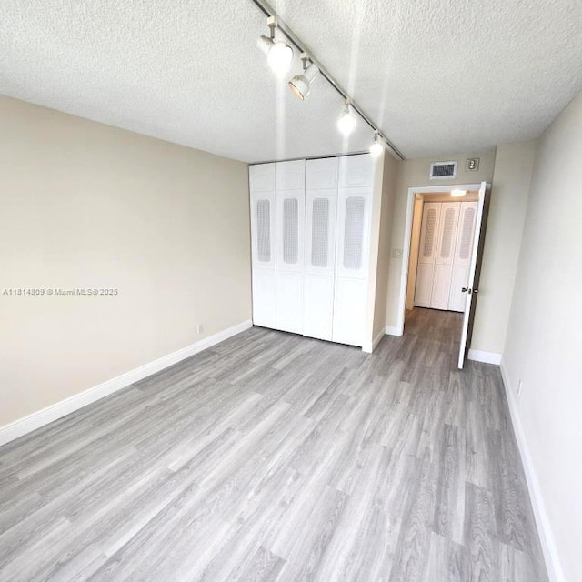 1801 S Flagler Dr Unit 1505, West Palm Beach, FL 33401 - unfurnished bedroom featuring a textured ceiling, wood finished floors, baseboards, a closet, and rail lighting