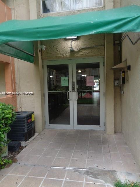 9320 Fontainebleau Blvd Unit 503, Miami, FL 33172 - view of exterior entry with french doors, central AC, and stucco siding