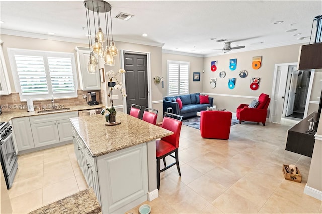 3063 NW 126th Ave, Sunrise, FL 33323 - kitchen with a breakfast bar area, crown molding, a center island, a ceiling fan, and light stone counters