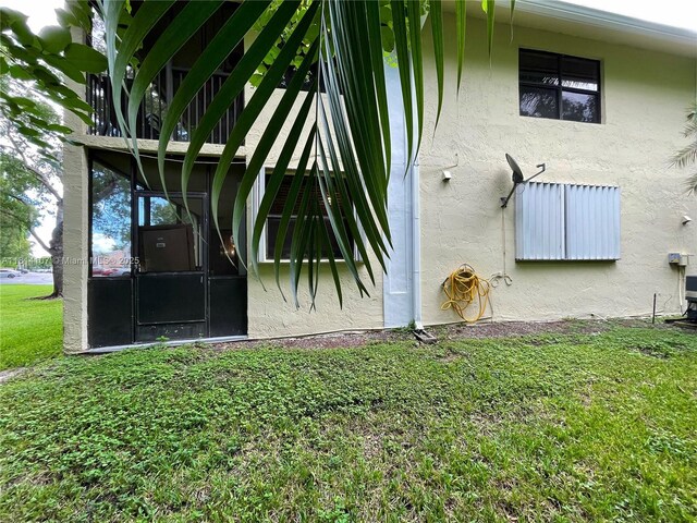 1150 N Liberty Ave Unit K, Homestead, FL 33034 - view of side of property featuring stucco siding, a lawn, and a sunroom