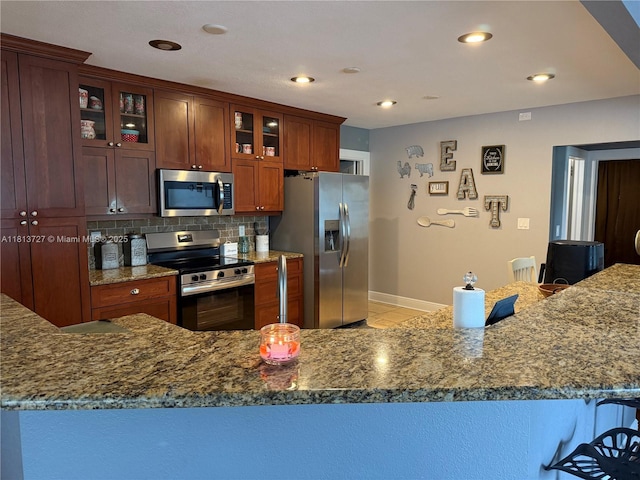 416 N Deane Duff Ave, Clewiston, FL 33440 - kitchen featuring appliances with stainless steel finishes, stone counters, baseboards, decorative backsplash, and glass insert cabinets