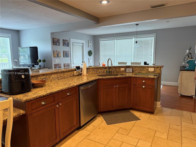 416 N Deane Duff Ave, Clewiston, FL 33440 - kitchen with stainless steel dishwasher, a sink, light stone counters, brown cabinetry, and pendant lighting