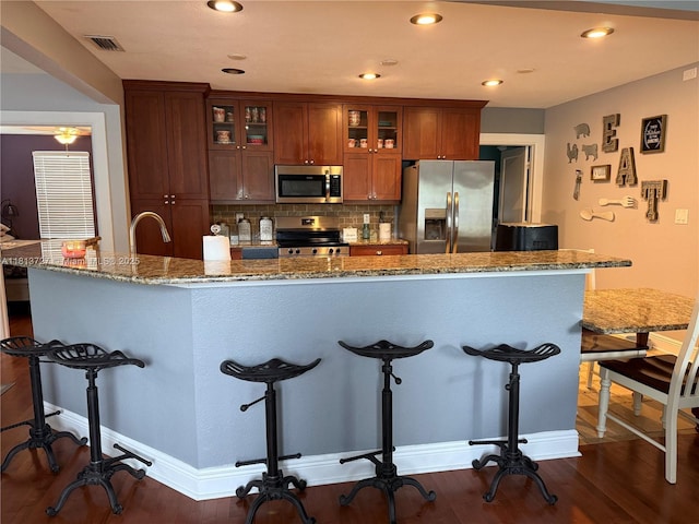 416 N Deane Duff Ave, Clewiston, FL 33440 - kitchen with stainless steel appliances, a kitchen breakfast bar, decorative backsplash, recessed lighting, and glass insert cabinets