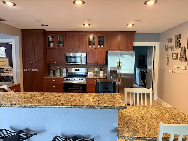 416 N Deane Duff Ave, Clewiston, FL 33440 - kitchen featuring appliances with stainless steel finishes, backsplash, glass insert cabinets, light stone countertops, and baseboards