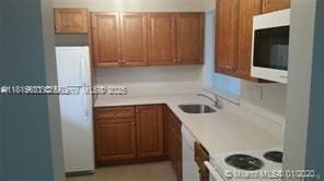 8045 SW 107th Ave Unit 323, Miami, FL 33173 - kitchen featuring white appliances, a sink, light countertops, and brown cabinetry