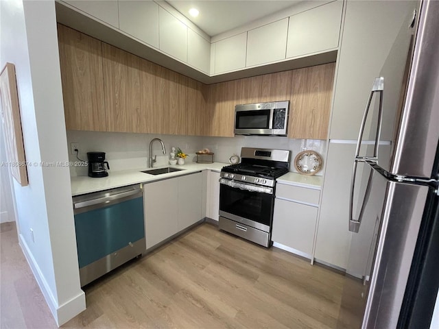 1619 Jefferson Ave Unit 19, Miami Beach, FL 33139 - kitchen with appliances with stainless steel finishes, a sink, light countertops, light wood-style flooring, and modern cabinets