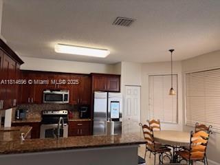 16362 SW 23rd St, Miramar, FL 33027 - kitchen with appliances with stainless steel finishes, a peninsula, dark brown cabinets, pendant lighting, and decorative backsplash