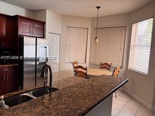 16362 SW 23rd St, Miramar, FL 33027 - kitchen with stainless steel refrigerator, a sink, light tile patterned floors, decorative light fixtures, and baseboards