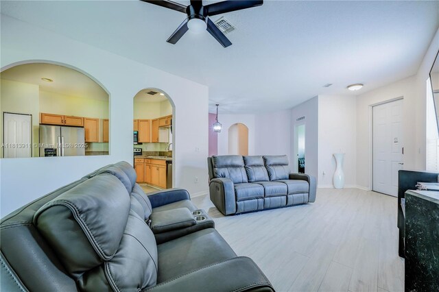 9722 SW Glenbrook Dr, Port St Lucie, FL 34987 - living area featuring arched walkways, ceiling fan, baseboards, and light wood-style flooring