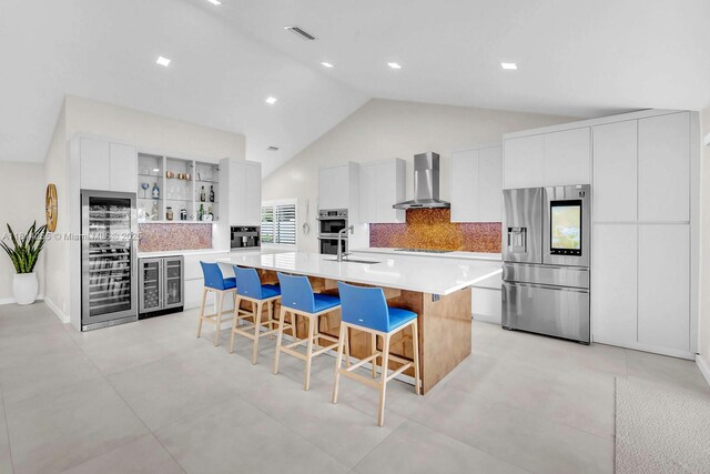 1240 NW 161st Ave, Pembroke Pines, FL 33028 - kitchen with stainless steel appliances, wall chimney exhaust hood, wine cooler, a breakfast bar area, and high vaulted ceiling