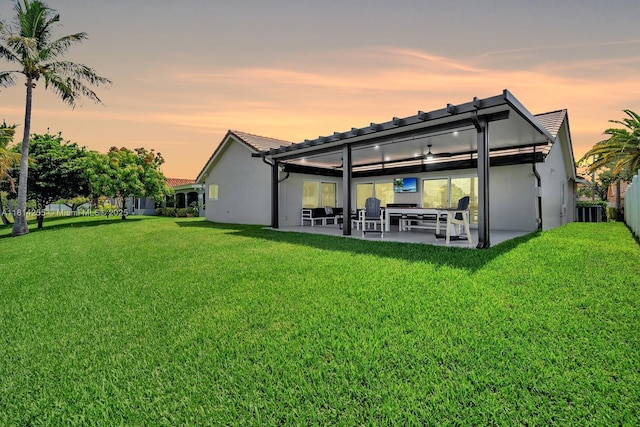 1240 NW 161st Ave, Pembroke Pines, FL 33028 - back of house at dusk with a patio, a lawn, stucco siding, and a tile roof