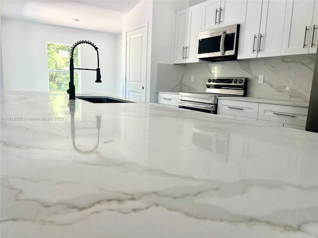 8036 104th Ct, Vero Beach, FL 32967 - kitchen featuring stainless steel appliances, tasteful backsplash, light stone counters, and white cabinetry