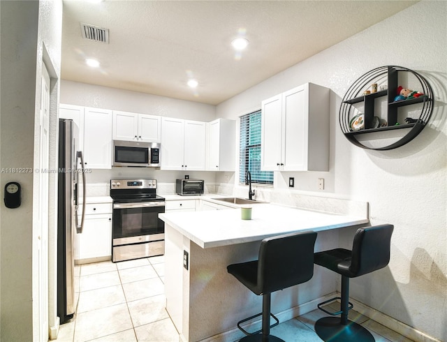 6489 N Anise Ct, Davie, FL 33314 - kitchen with stainless steel appliances, a sink, a peninsula, a kitchen breakfast bar, and white cabinets