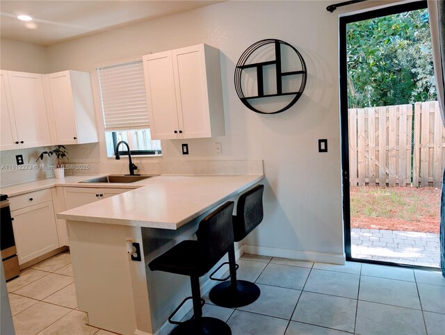 6489 N Anise Ct, Davie, FL 33314 - kitchen featuring a kitchen breakfast bar, white cabinets, light countertops, a peninsula, and light tile patterned flooring