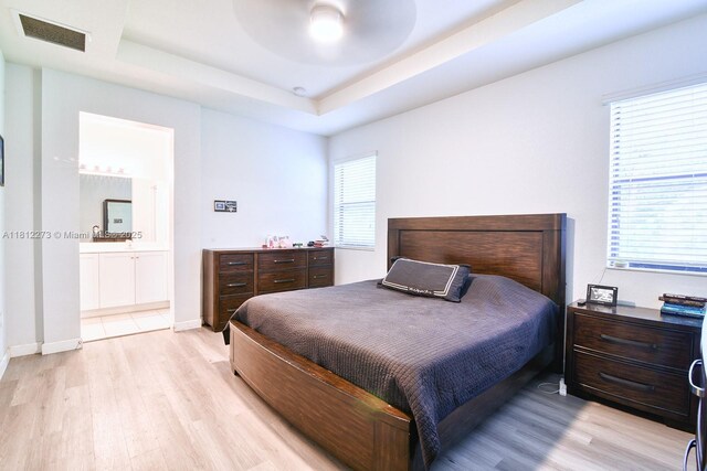 6489 N Anise Ct, Davie, FL 33314 - bedroom featuring light wood-style floors, a tray ceiling, ensuite bathroom, and ceiling fan