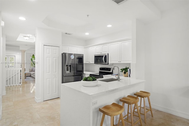 615 Santander Ave Unit C, Coral Gables, FL 33134 - kitchen featuring appliances with stainless steel finishes, a sink, a peninsula, white cabinets, and ornate columns