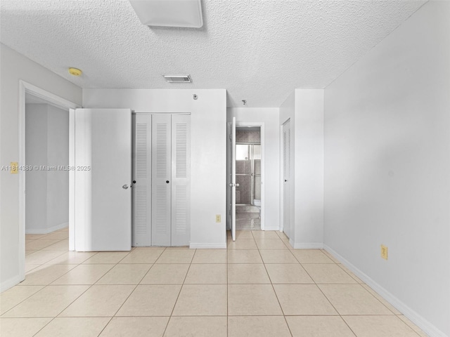 7905 W 30th Ct Unit 204, Hialeah, FL 33018 - unfurnished bedroom featuring tile patterned flooring, multiple closets, a textured ceiling, baseboards, and ensuite bath