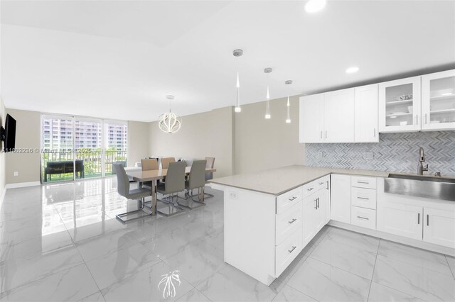 2851 NE 183rd St Unit 510E, Aventura, FL 33160 - kitchen featuring a sink, light marble finish flooring, a peninsula, tasteful backsplash, and white cabinets