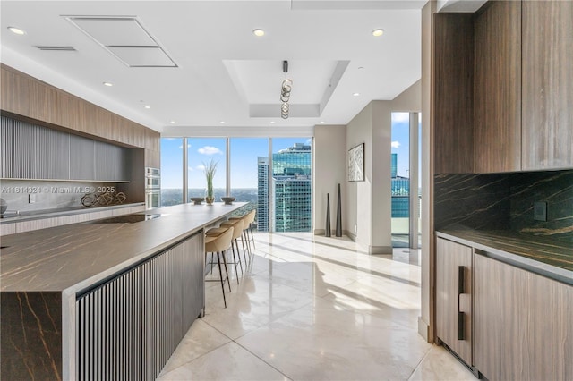 1300 Brickell Bay Dr Unit 4400, Miami, FL 33131 - kitchen featuring modern cabinets, a raised ceiling, dark countertops, floor to ceiling windows, and recessed lighting