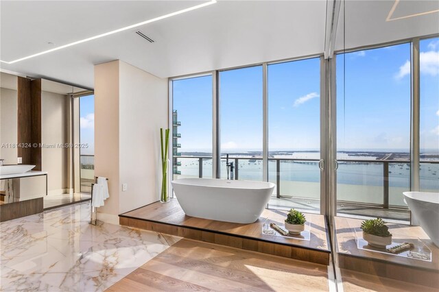 1300 Brickell Bay Dr Unit 4400, Miami, FL 33131 - bathroom featuring a water view, a freestanding tub, floor to ceiling windows, marble tiled floors, and vanity