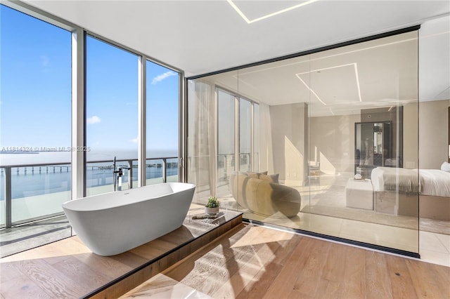 1300 Brickell Bay Dr Unit 4400, Miami, FL 33131 - full bathroom featuring a water view, wood finished floors, a freestanding tub, and a wall of windows