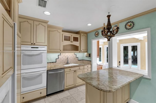 345 Harbor Ln, Key Biscayne, FL 33149 - kitchen with dishwasher, white double oven, a sink, cream cabinetry, and backsplash