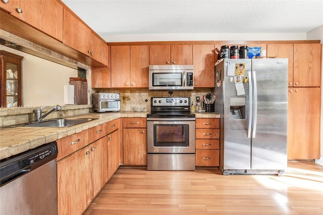 10630 NW 14th St Unit 115, Plantation, FL 33322 - kitchen featuring appliances with stainless steel finishes, a sink, light wood finished floors, tile counters, and tasteful backsplash