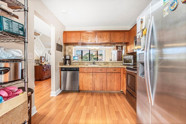 10630 NW 14th St Unit 115, Plantation, FL 33322 - kitchen featuring appliances with stainless steel finishes, light wood-style flooring, and brown cabinets