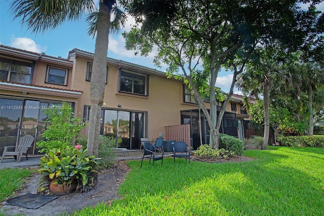 10630 NW 14th St Unit 115, Plantation, FL 33322 - back of property featuring stucco siding, a lawn, a sunroom, and a tile roof
