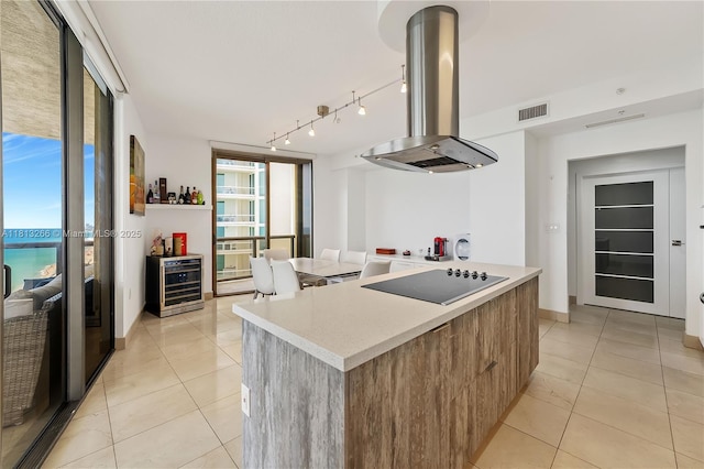 16275 Collins Ave Unit 2101, Sunny Isles Beach, FL 33160 - kitchen with island range hood, black electric stovetop, beverage cooler, light tile patterned floors, and light countertops